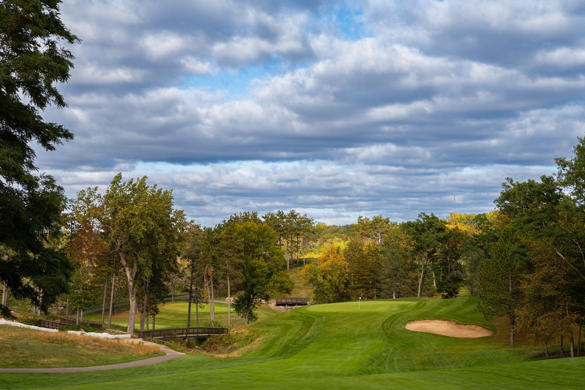 A golf course with trees and clouds in the sky