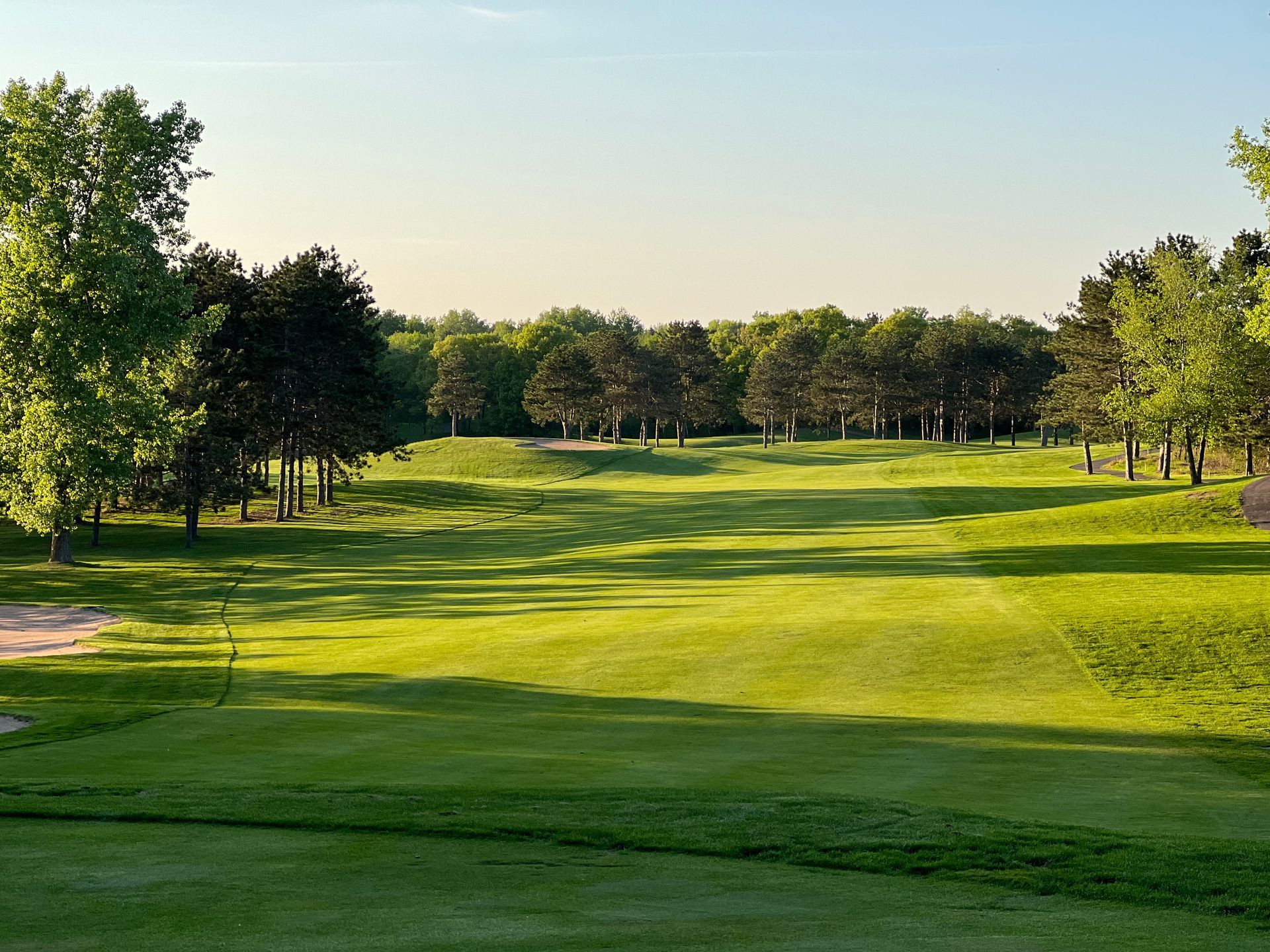 A golf course with a lot of green grass and trees in the background