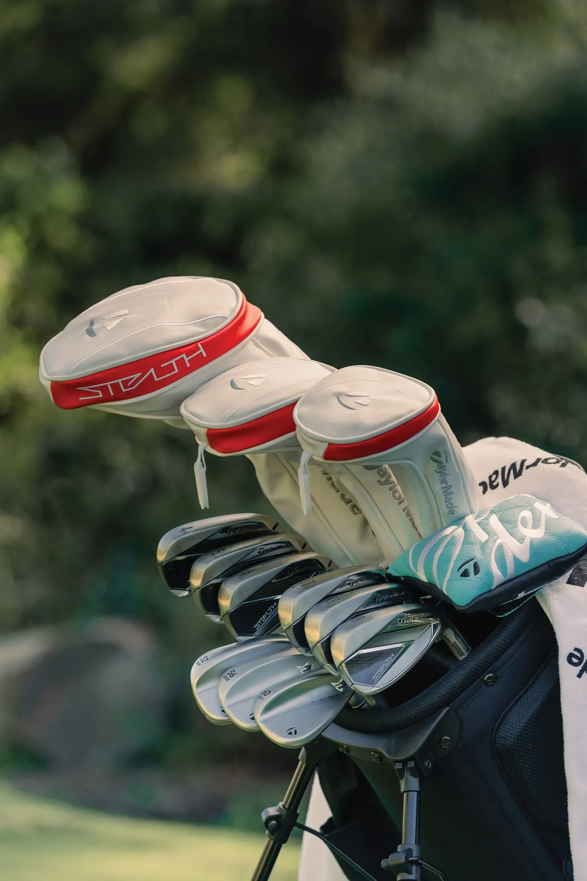 A close up of a golf bag filled with golf clubs on a golf course.