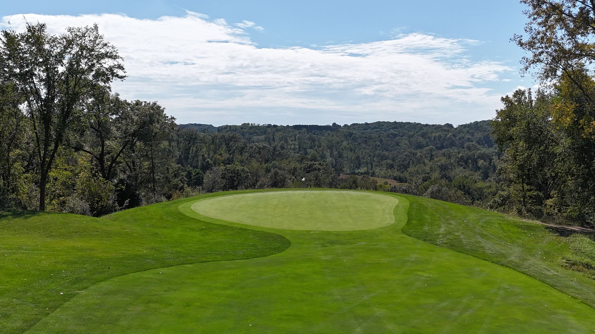 A golf course with trees and a blue sky in the background