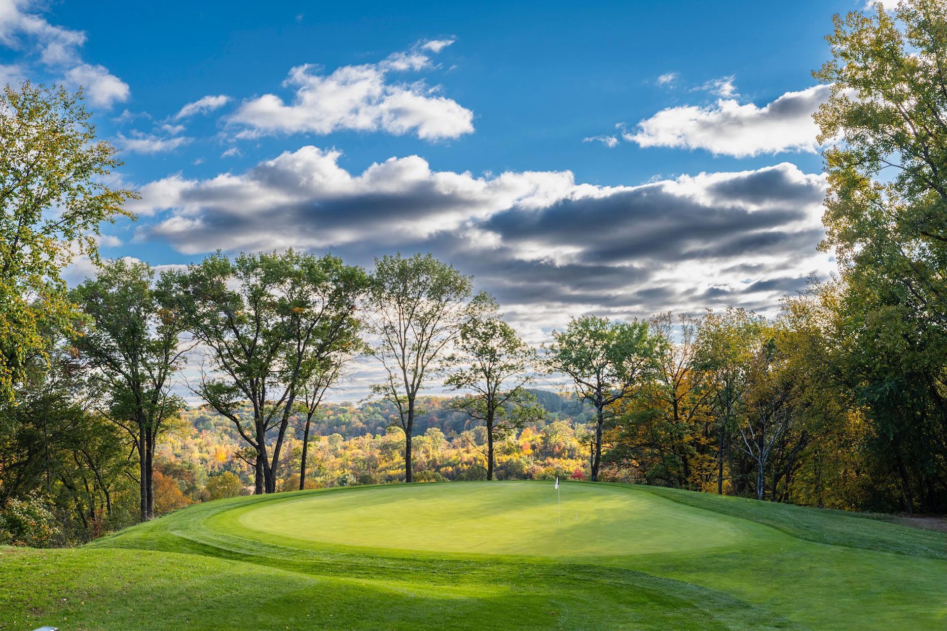 A golf course with trees and a blue sky in the background