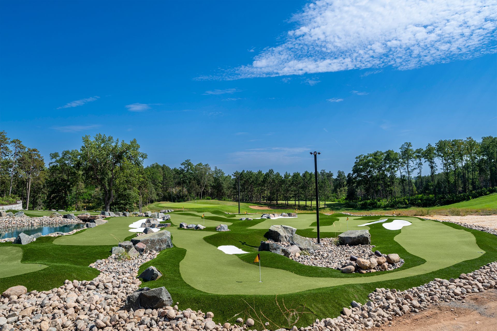 A small golf course surrounded by rocks and trees on a sunny day.