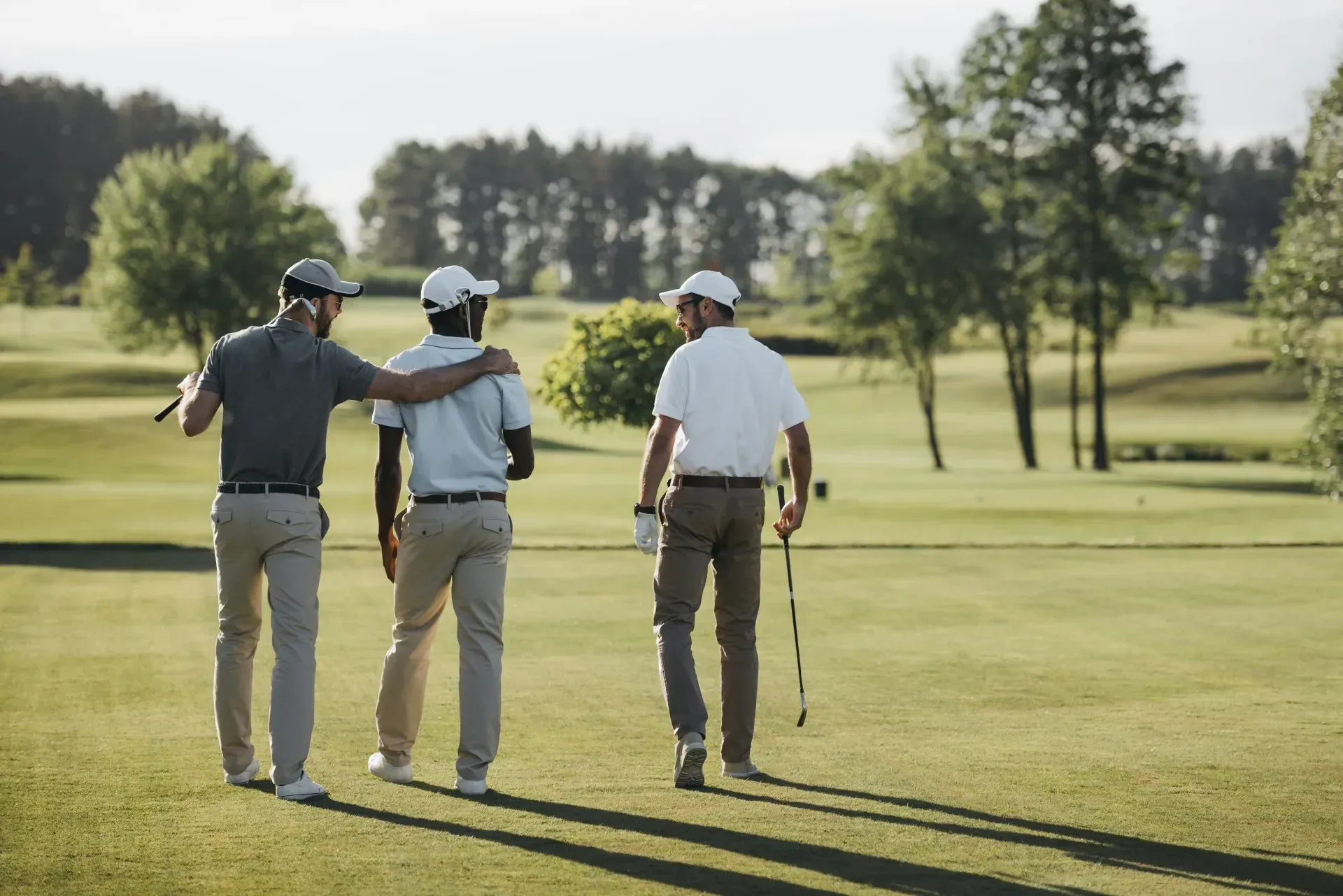 Three men are walking on a golf course holding golf clubs.