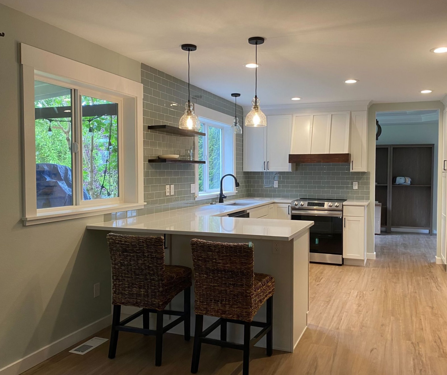 Bright modern kitchen with island, pendant lights, white cabinets, and bar stools