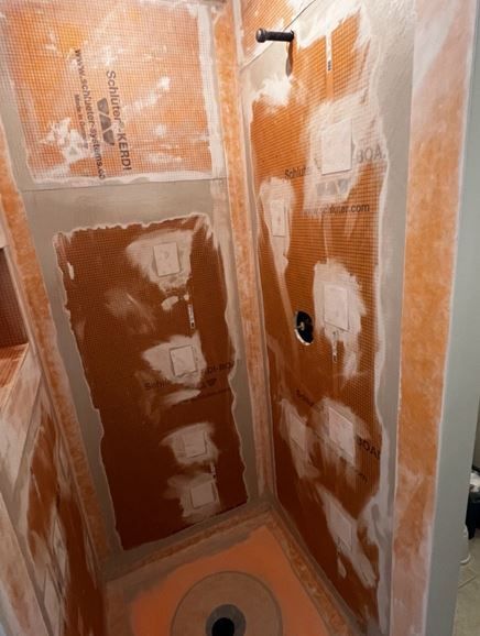 Schluter shower system | A shower stall is being remodeled in a bathroom.