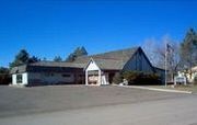 Church building with dark roof and white trim under a clear blue sky.