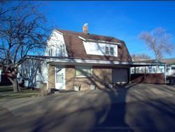 Two-story house with a brown roof and carport. Brown brick exterior with a blue sky background.
