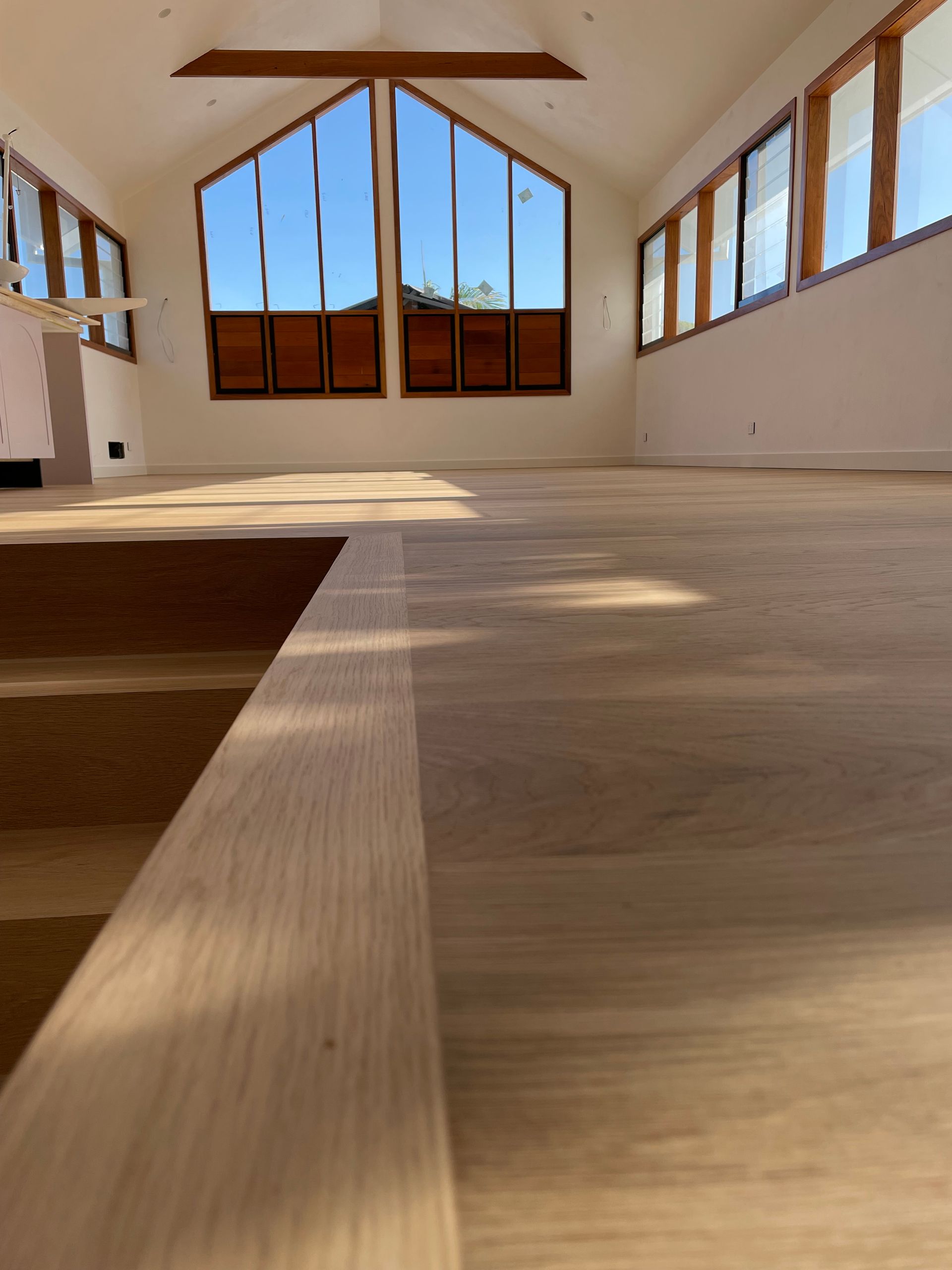 Light wood floor in a room with large windows, bright sky, and white walls — CM Timber Flooring in East Ballina, NSW