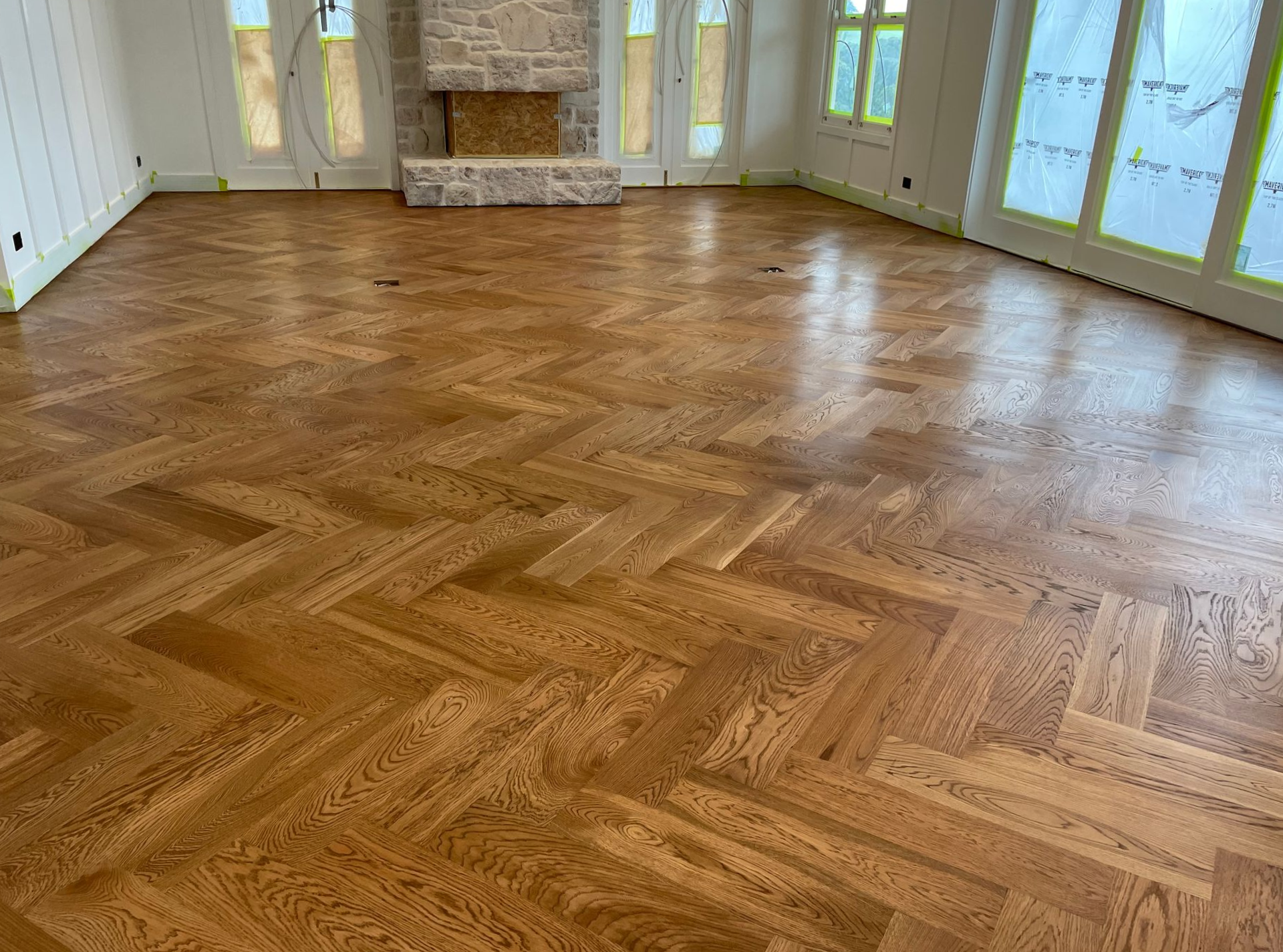 Refinished herringbone hardwood floor in a room with a fireplace and windows, reflecting light — CM Timber Flooring in East Ballina, NSW