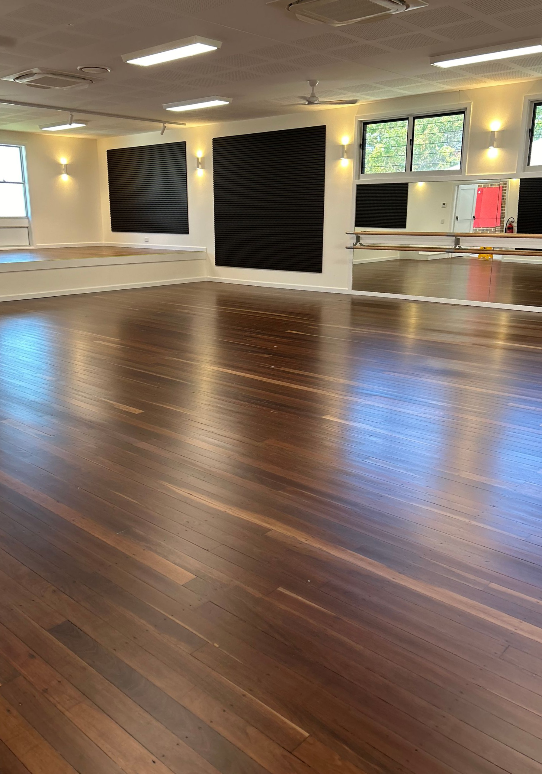 Wooden floor in a bright dance studio with mirrors, windows, and black abstract art on the walls — CM Timber Flooring in East Ballina, NSW