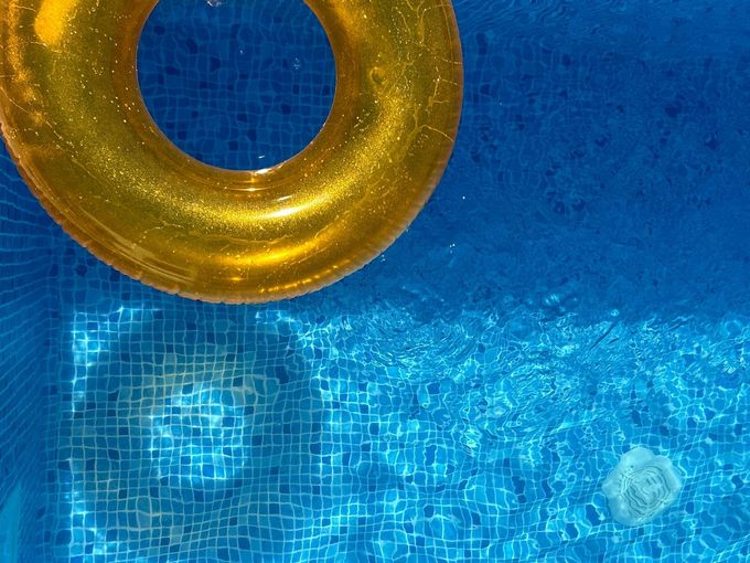 Blue swimming pool water with a gold inflatable ring floating at the top left