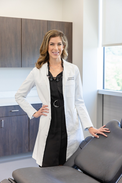 Ashley J. Guthrie MD standing next to medical exam room chair