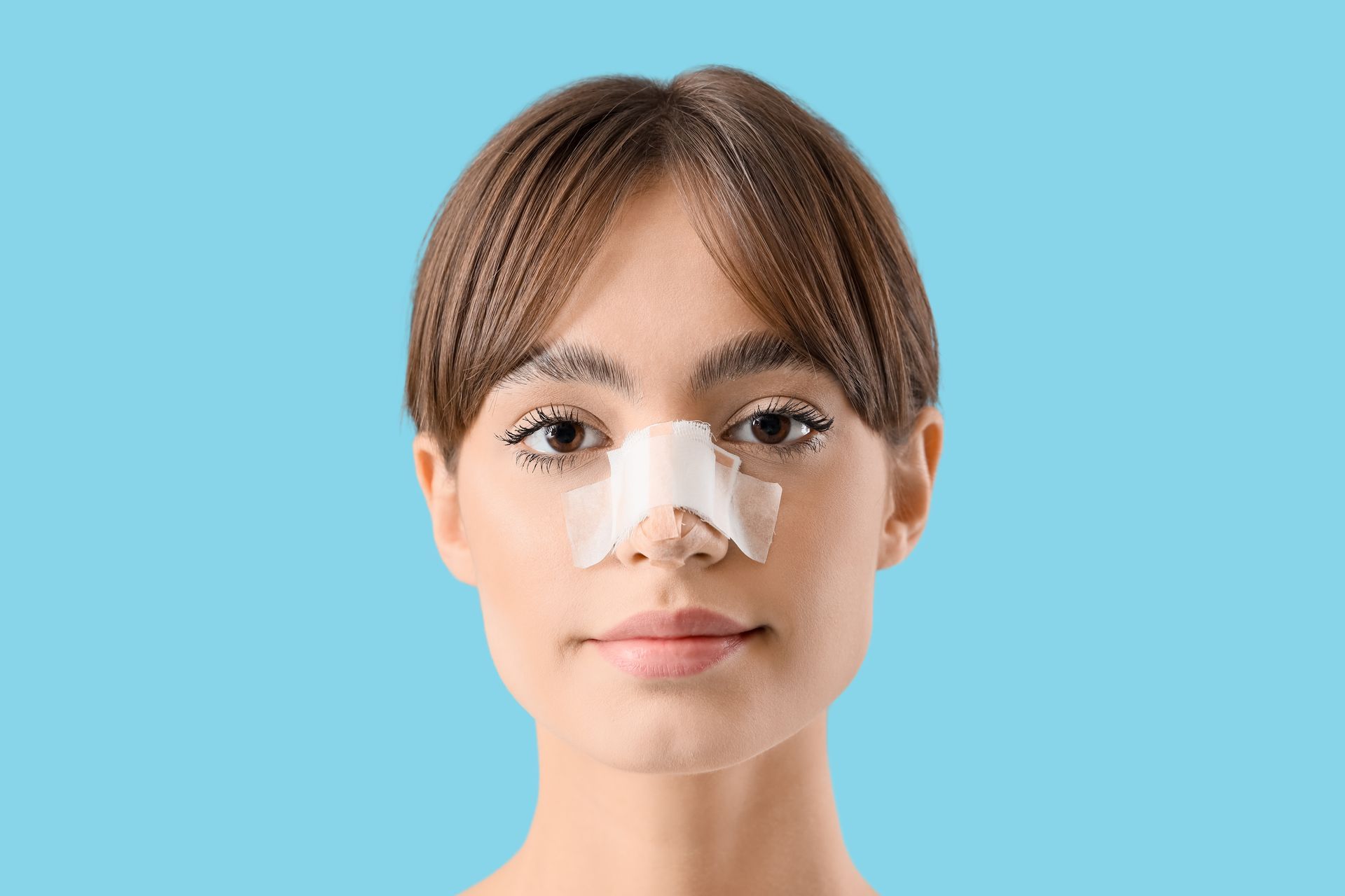Woman with white nose strips against a light blue background