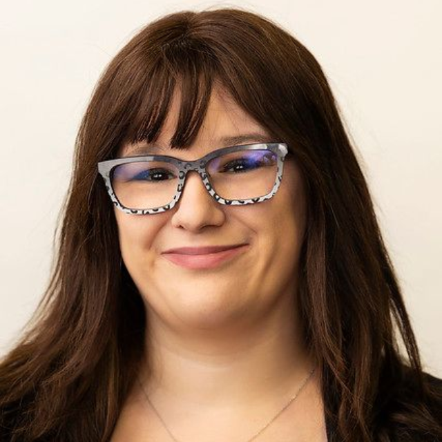 Portrait of a smiling person wearing blue glasses against a light background