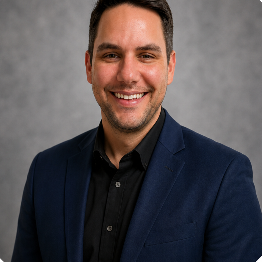 Smiling person in a navy blazer and black shirt against a gray studio background