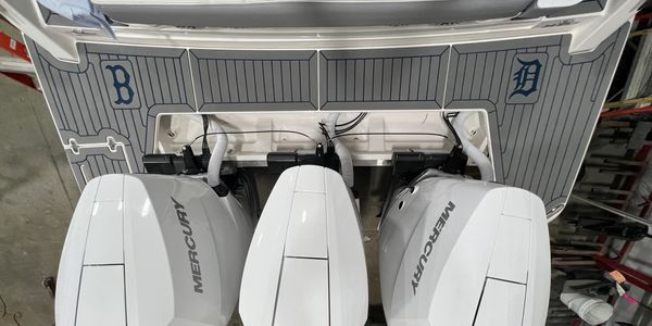 Three white speedboat sterns lined up in a marina with blue B markings on the dock walls