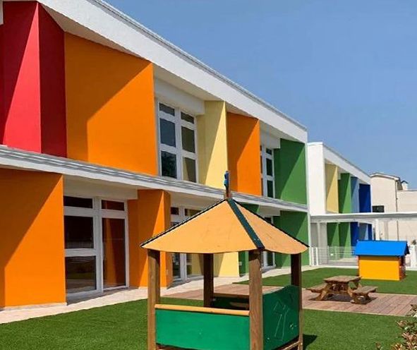 Asilo nido colorato con parco giochi; pareti rosse, arancioni, gialle, verdi e blu.