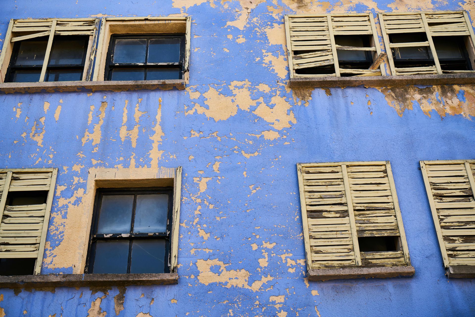 A blue building with yellow shutters on the windows