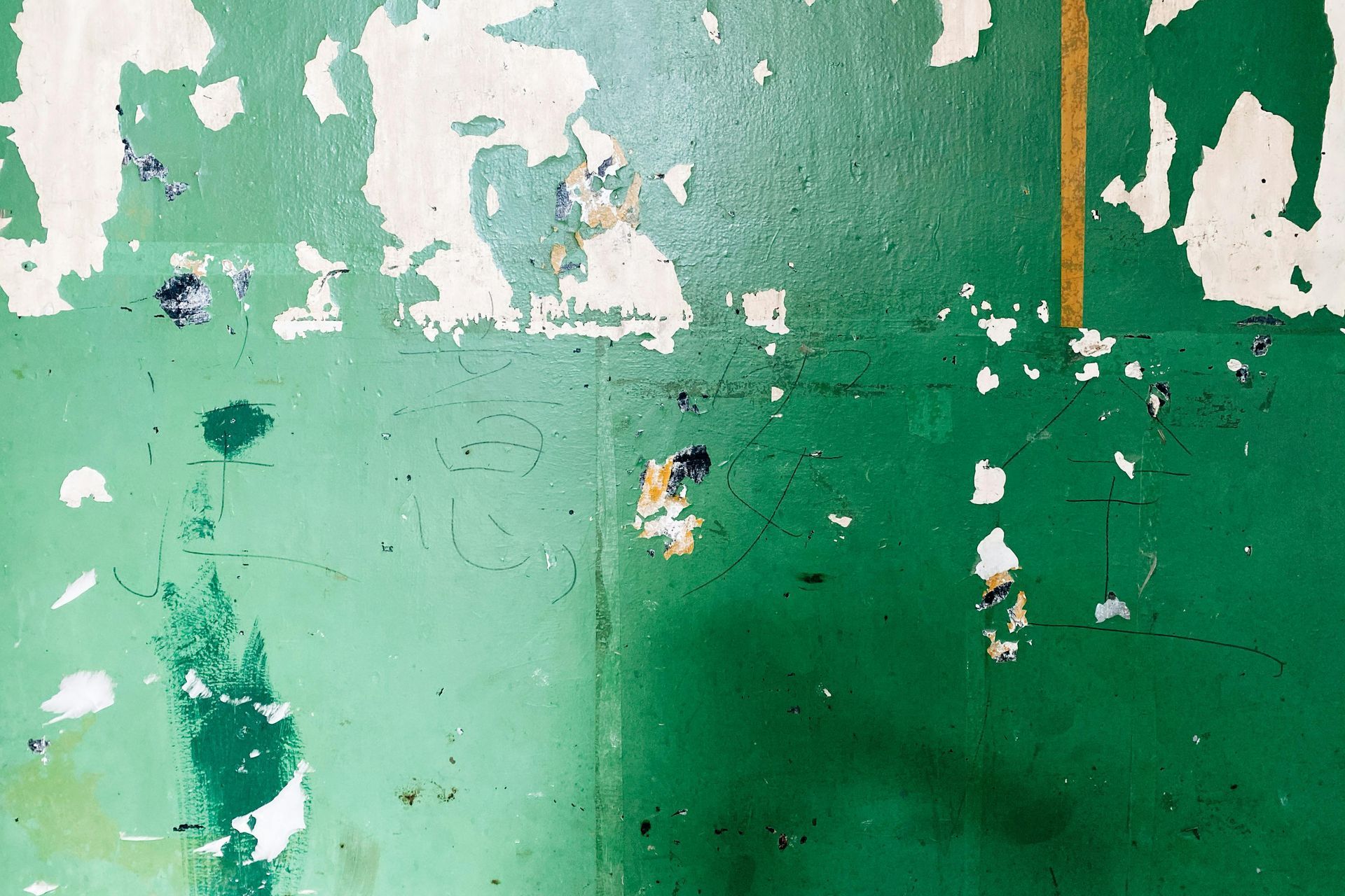 A green wall with white paint peeling off of it.