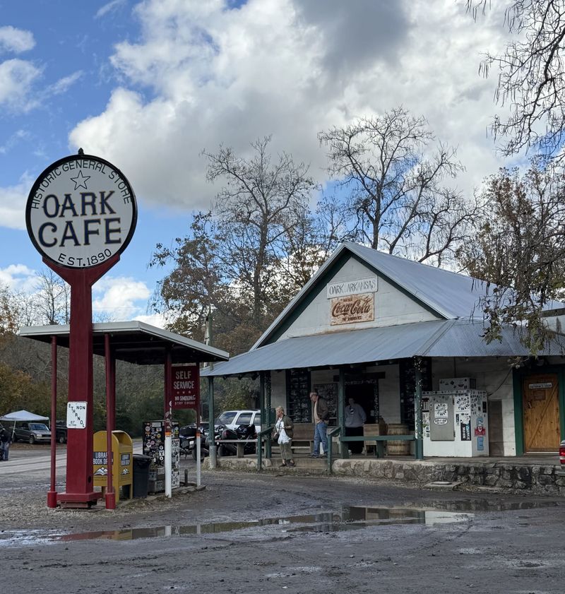 Rustic Oark Cafe storefront with large round sign, stone porch, and cloudy sky