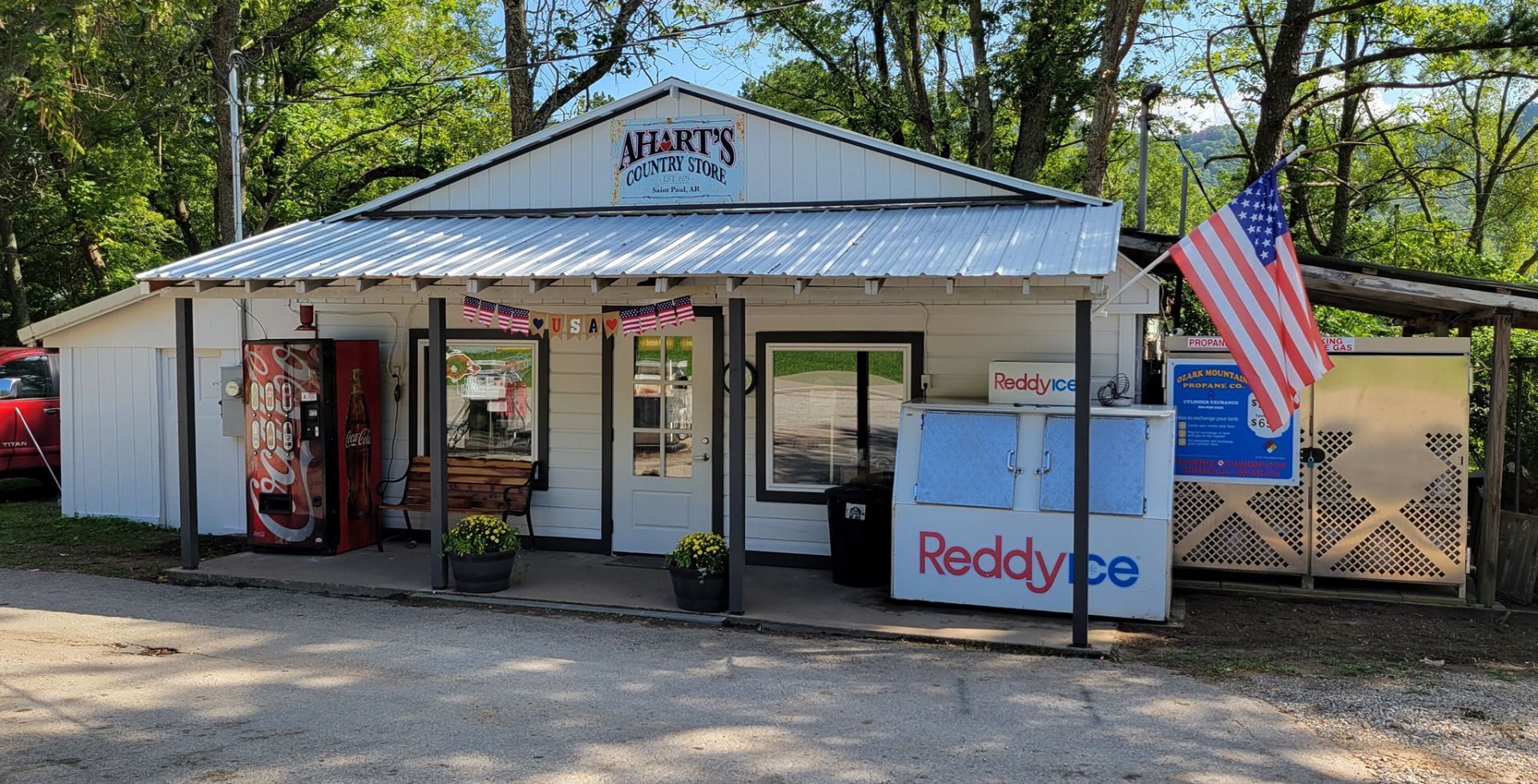 Small white storefront with a metal roof, American flag, and “Reddypay” sign by the entrance.