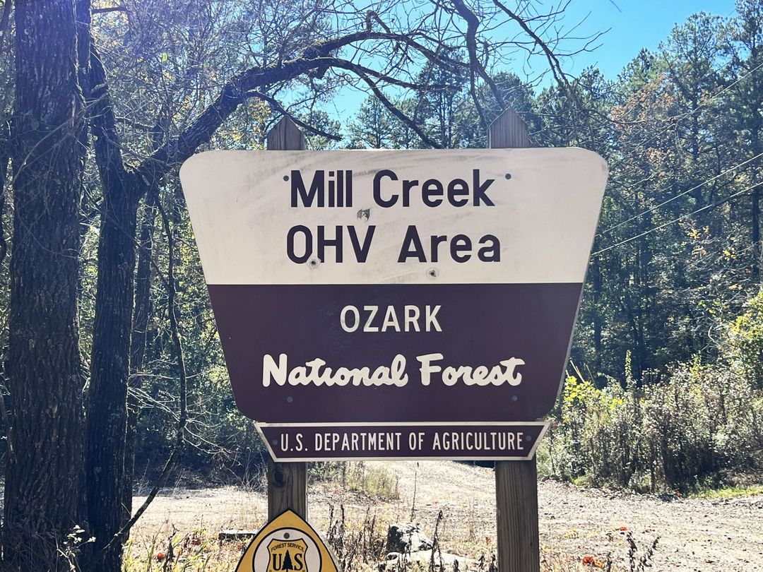 Mill Creek OHV Area sign in the Ozark National Forest beside a wooded trail