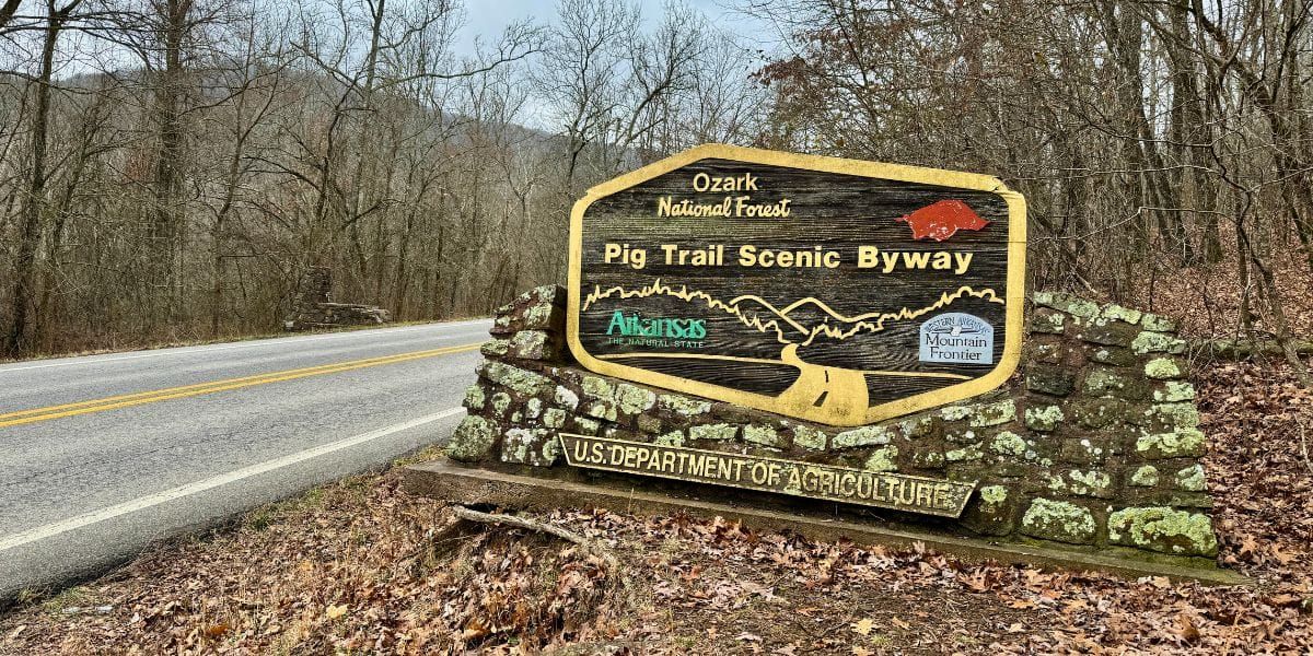 Roadside stone sign for the Blue Ridge Parkway in a wooded area beside a highway