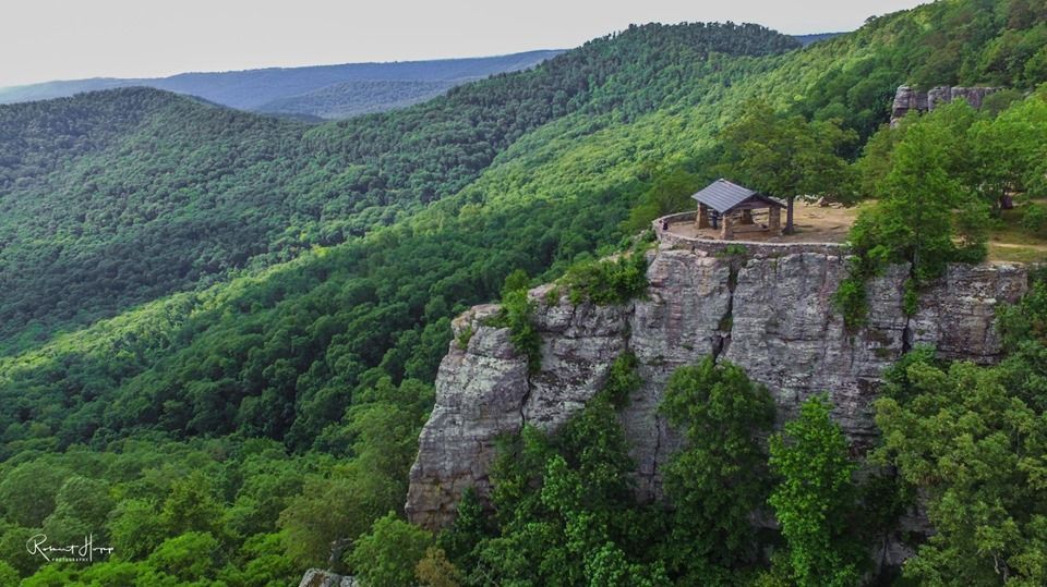 Wooden lookout on a rocky cliff overlooking a lush green mountain valley