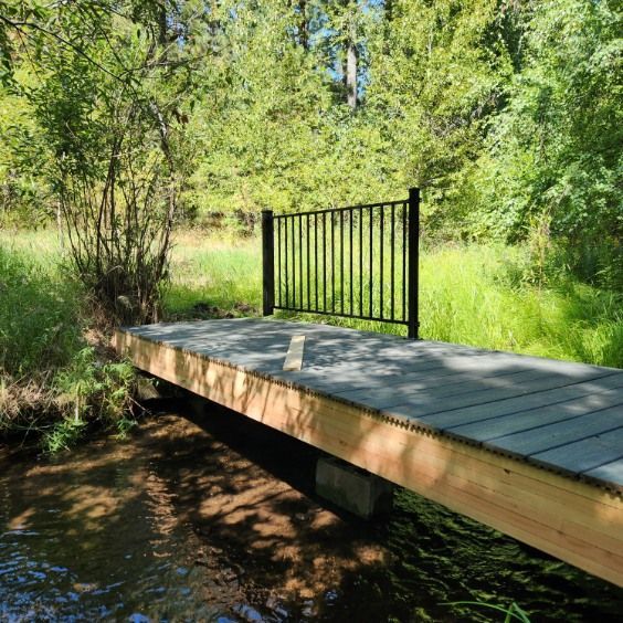 Small wooden footbridge over a creek in a green wooded park