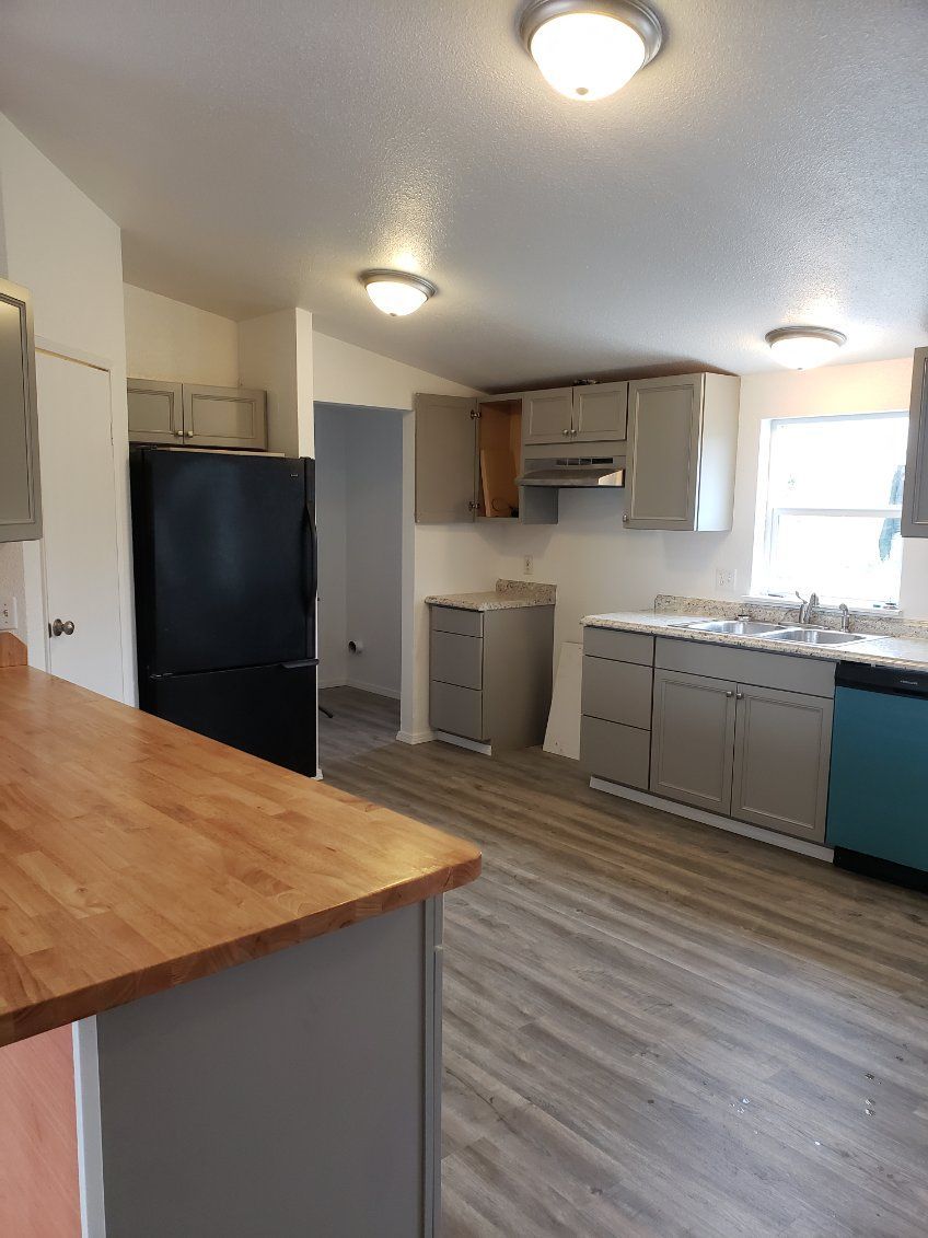 Modern kitchen with black fridge, wood island, gray cabinets, and two ceiling lights
