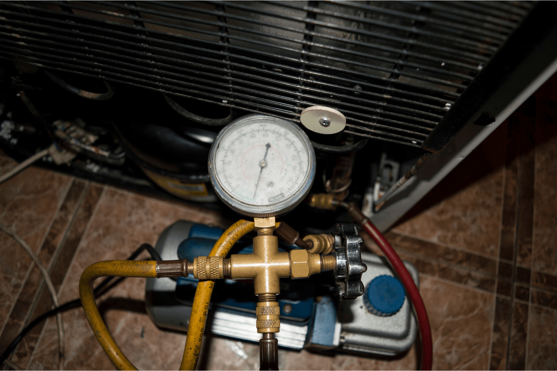 Pressure gauge and hoses attached to a HVAC or refrigeration unit.