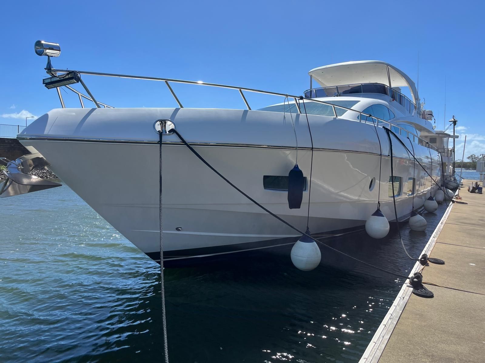 A White Motor Yacht Docked at a Marina on a Sunny Day — Ocean Mate Marine Services in Coomera, QLD