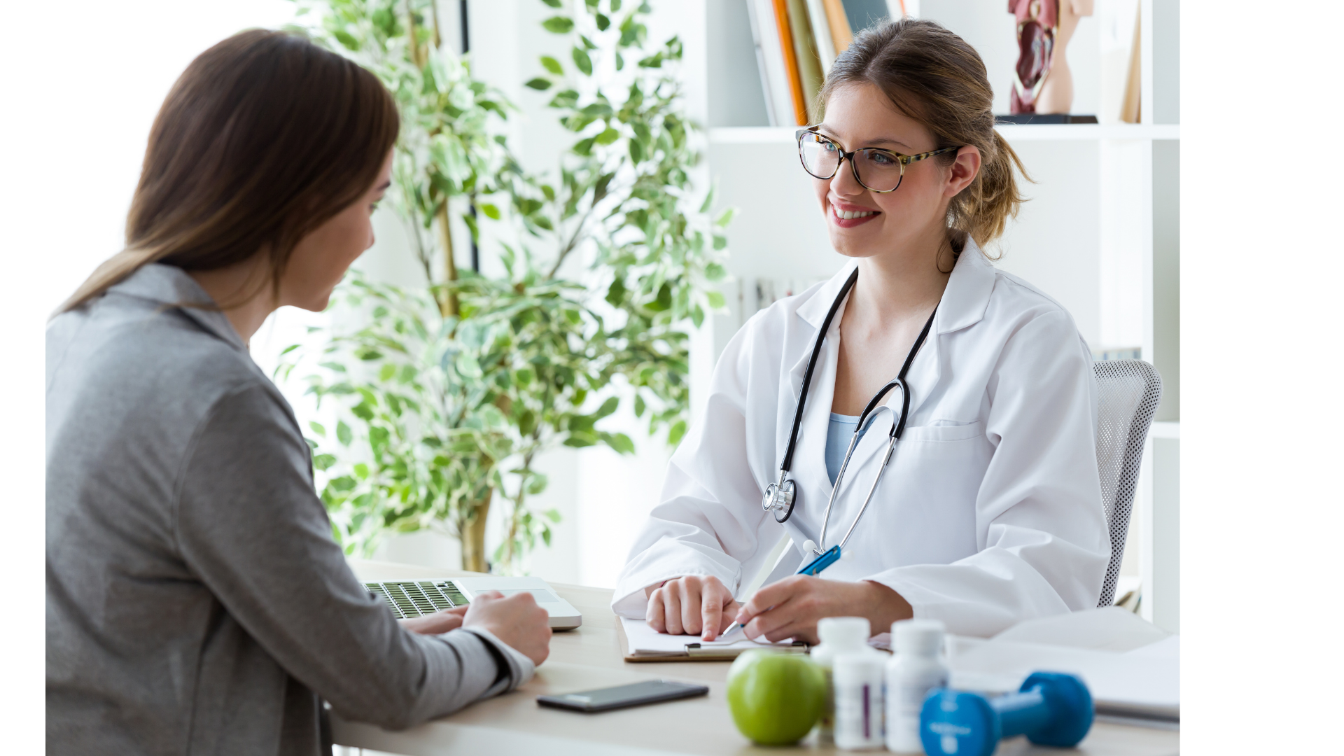 Een vrouw zit aan een tafel en praat met een dokter.