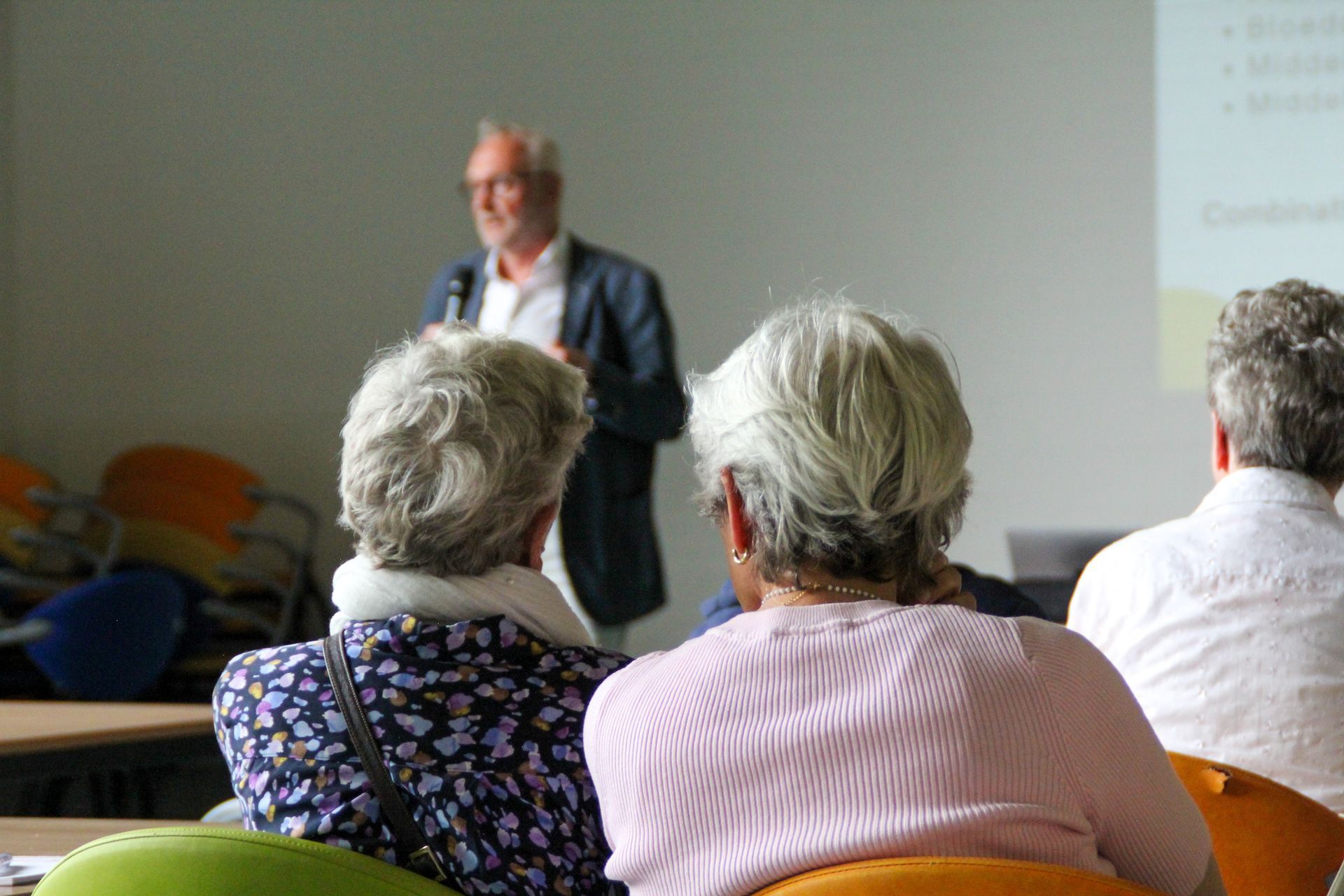 Publiek luistert naar een spreker tijdens een presentatie.
