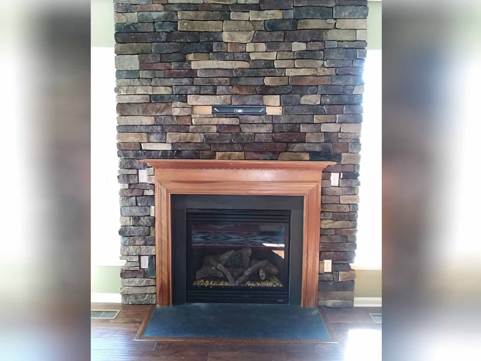 a fireplace with a brick wall and a wooden mantle in a living room .