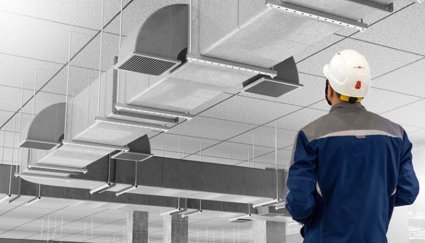 A man in a hard hat is looking at the ceiling of a building.
