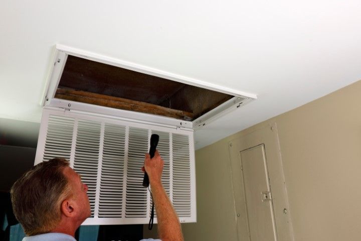 A man is looking through a hole in the ceiling.