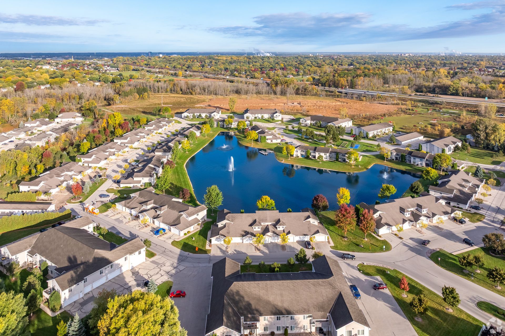 Aerial view of a suburban neighborhood centered around a blue pond and surrounding houses.