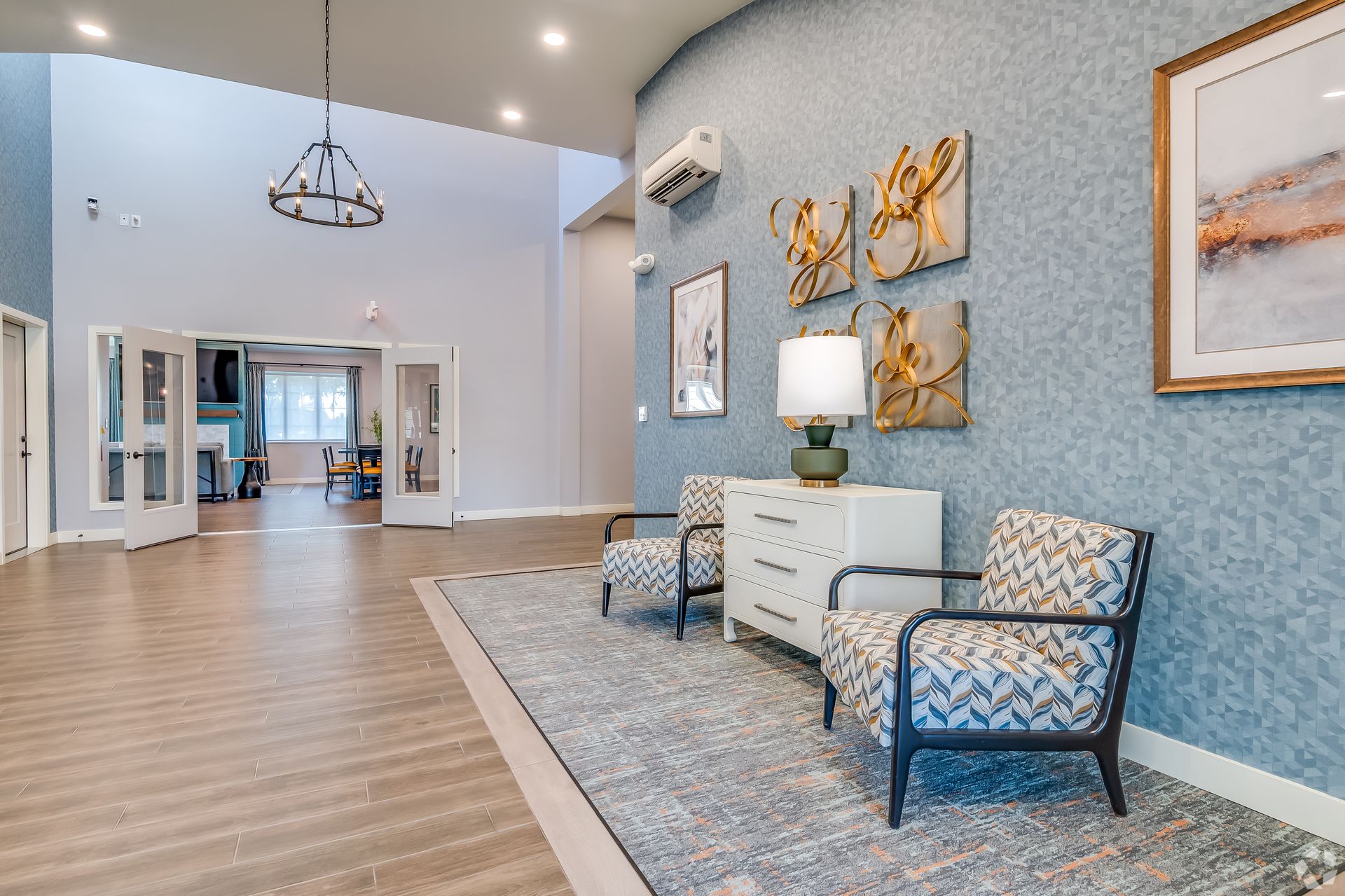 Modern waiting area with blue walls, patterned chairs, white cabinet, and wood flooring