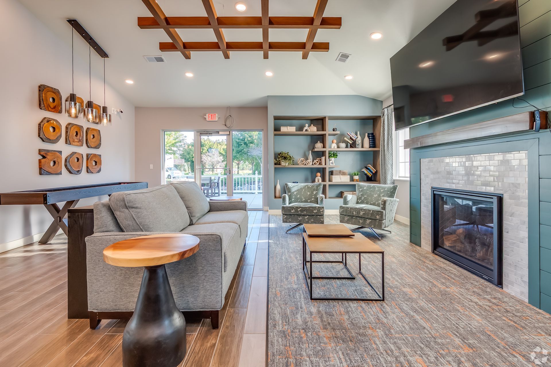 Cozy living room with gray sofa, fireplace, TV, shelving, and sliding glass doors to a patio