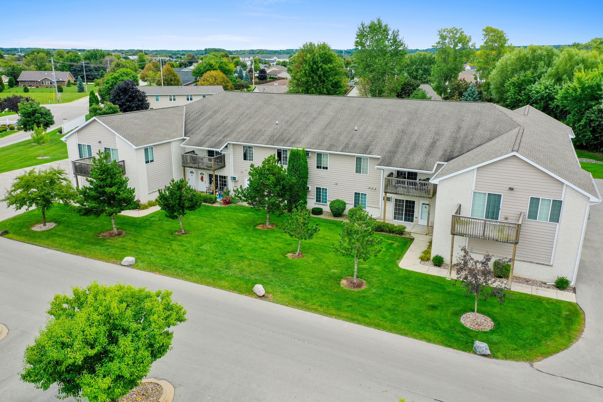 Aerial view of a large white suburban house with a green lawn and tree-lined street.