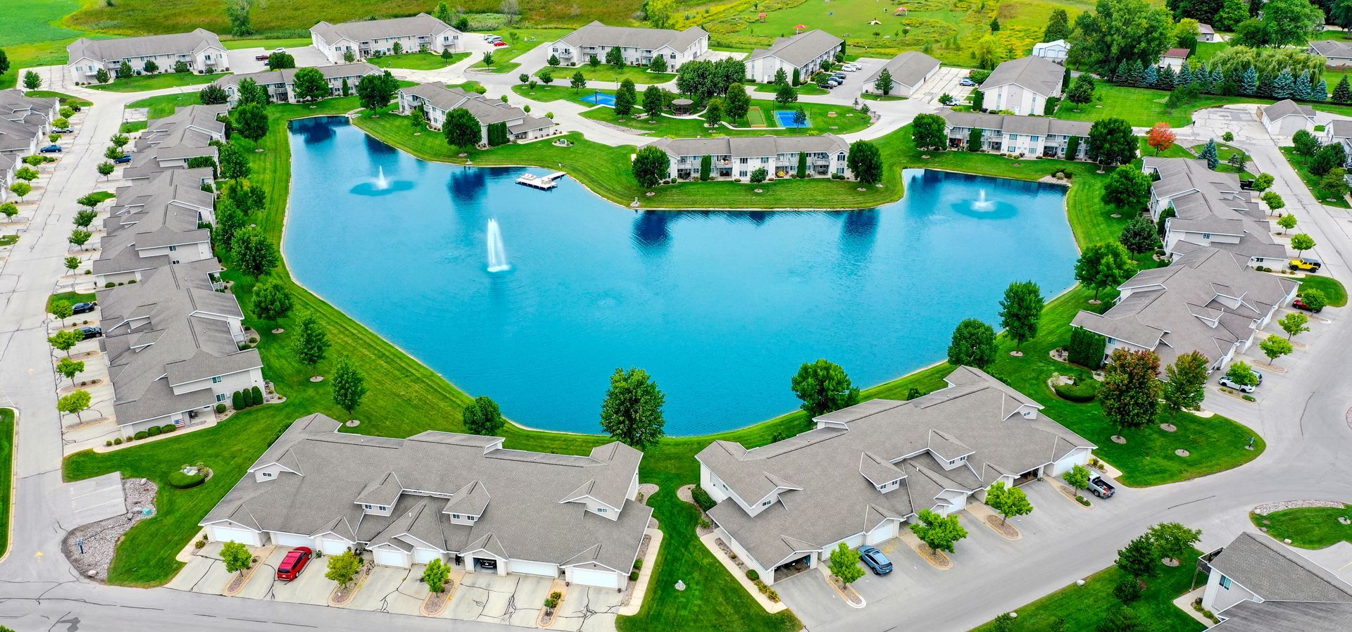 Aerial view of a lake surrounded by apartment buildings and green lawns