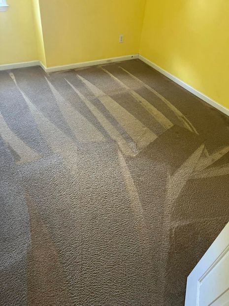 Yellow room with a partially covered carpet floor and visible cleaning marks.