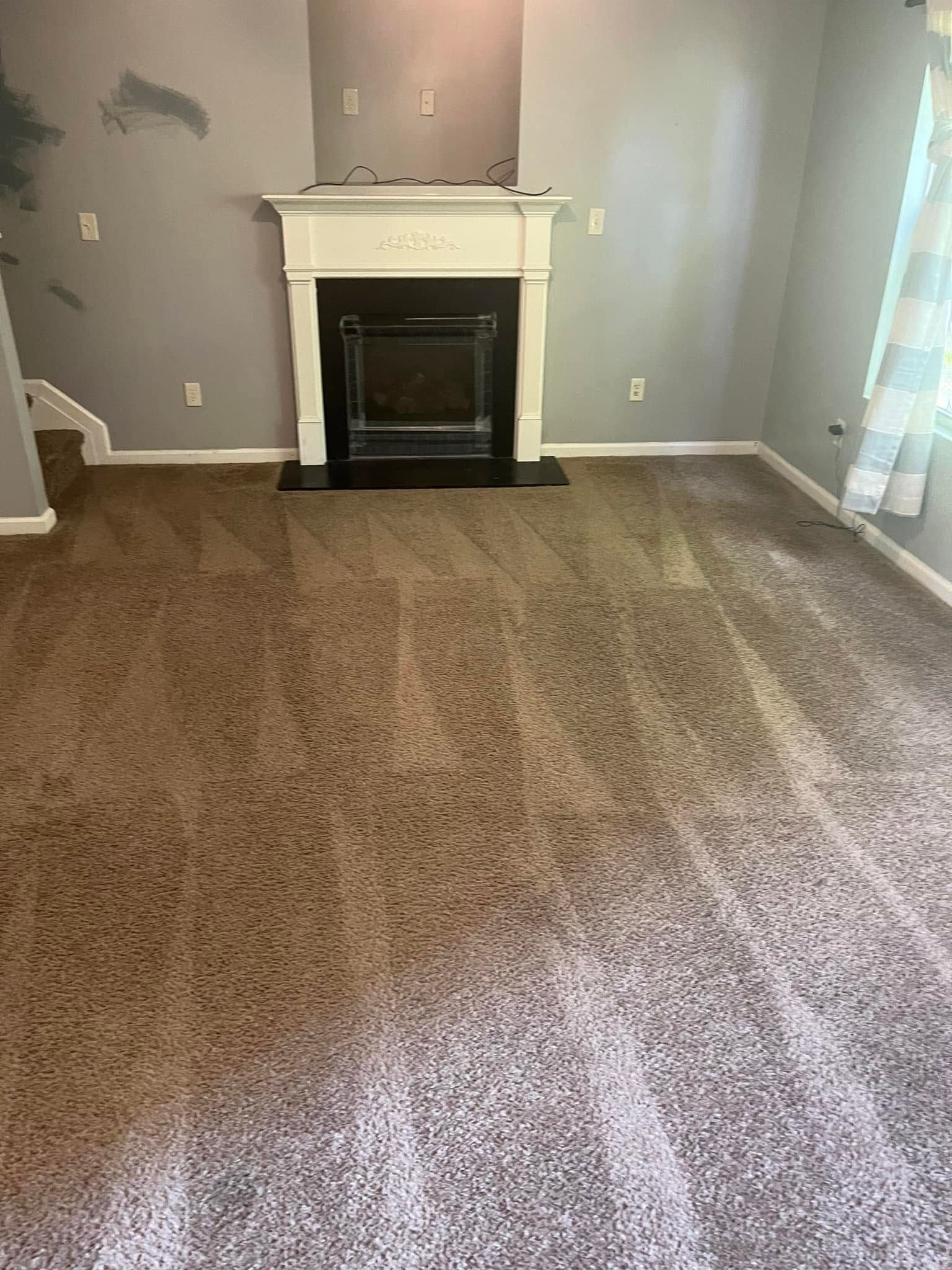 Empty living room with beige carpet and a white fireplace on a gray wall.