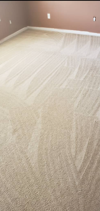 Empty beige carpeted room with taupe walls and white baseboards