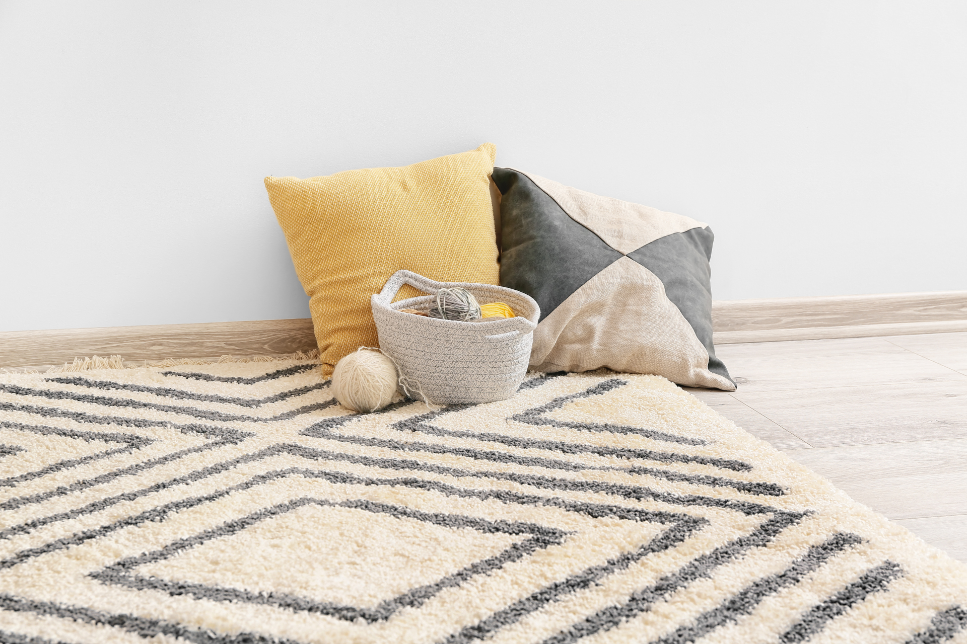 Cozy living room rug with decorative pillows and a small basket on a light floor