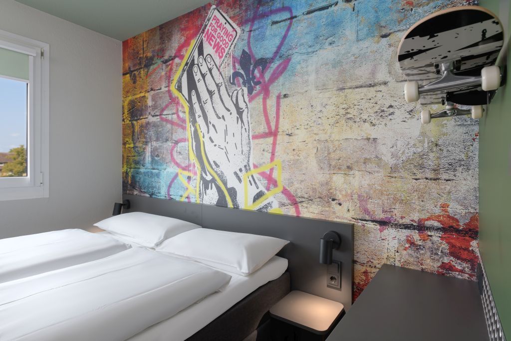 Modernes Schlafzimmer in der Nähe vom Hauptbahnhof mit einer Akzentwand, zwei Einzelbetten und einem runden Wandspiegel