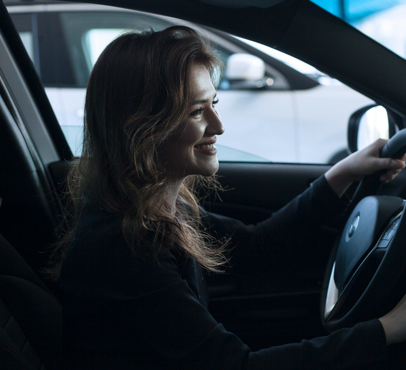 Woman driving a car, smiling in the driver’s seat
