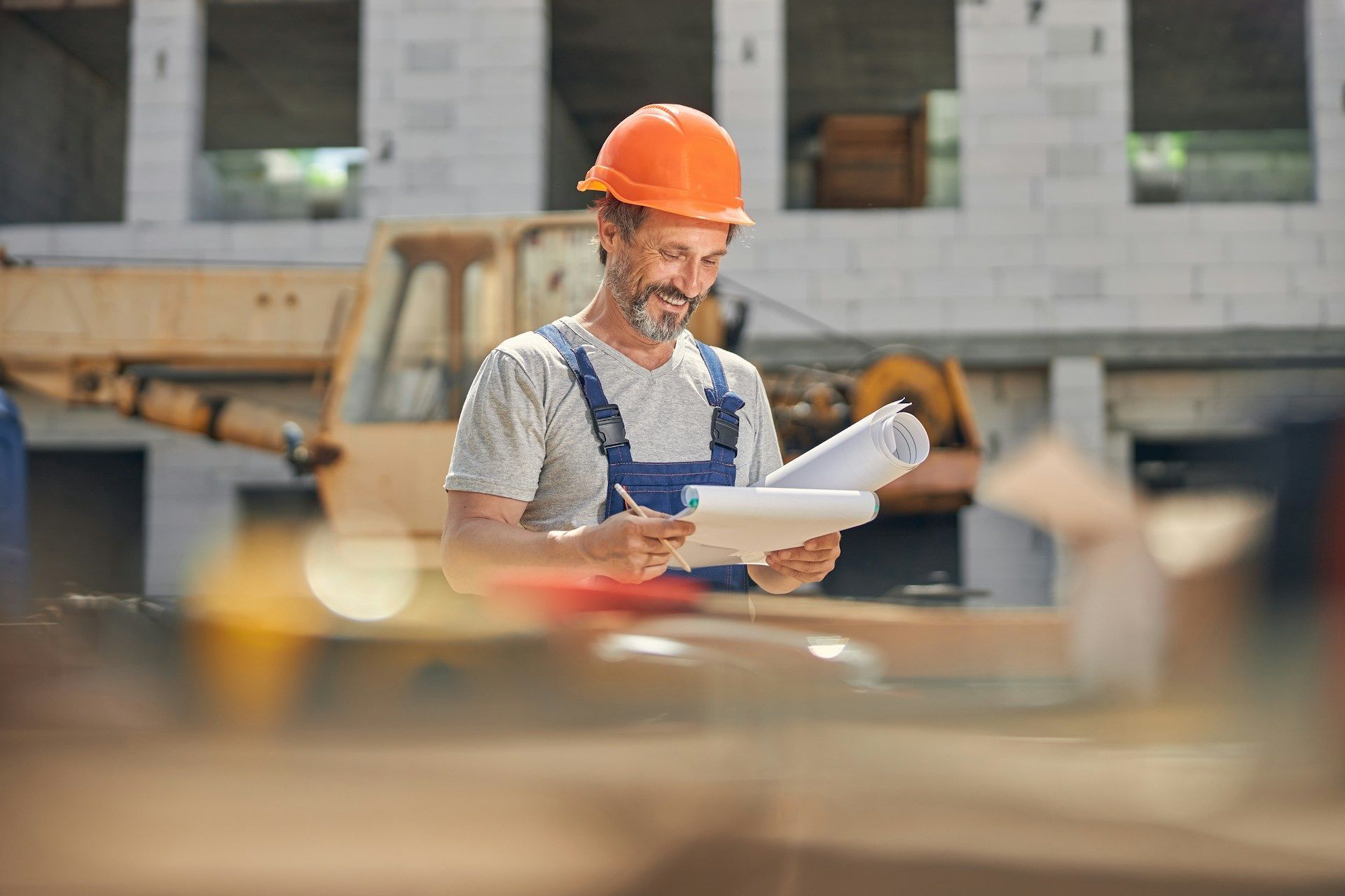 Construction worker in orange hard hat reviewing plans on a building site