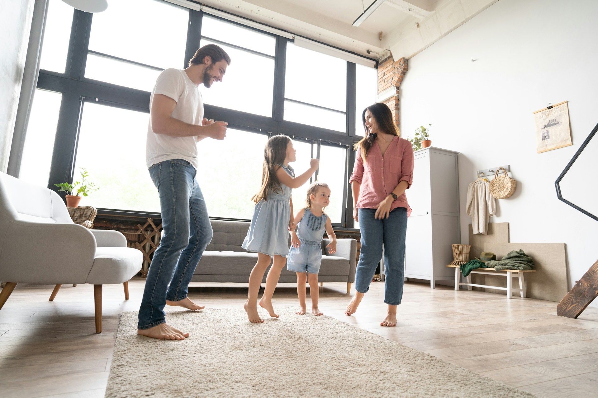 Family dancing together in a bright living room with large windows and a light rug